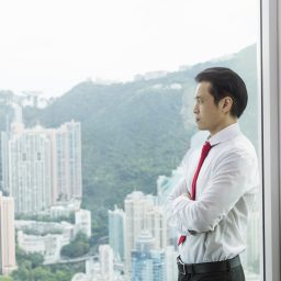 Businessman, arms folded looking out of window